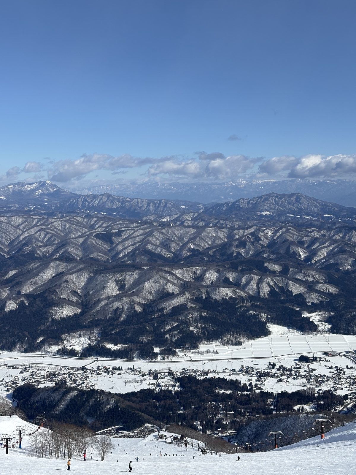 谷あいの集落と雪山、手前にリフト