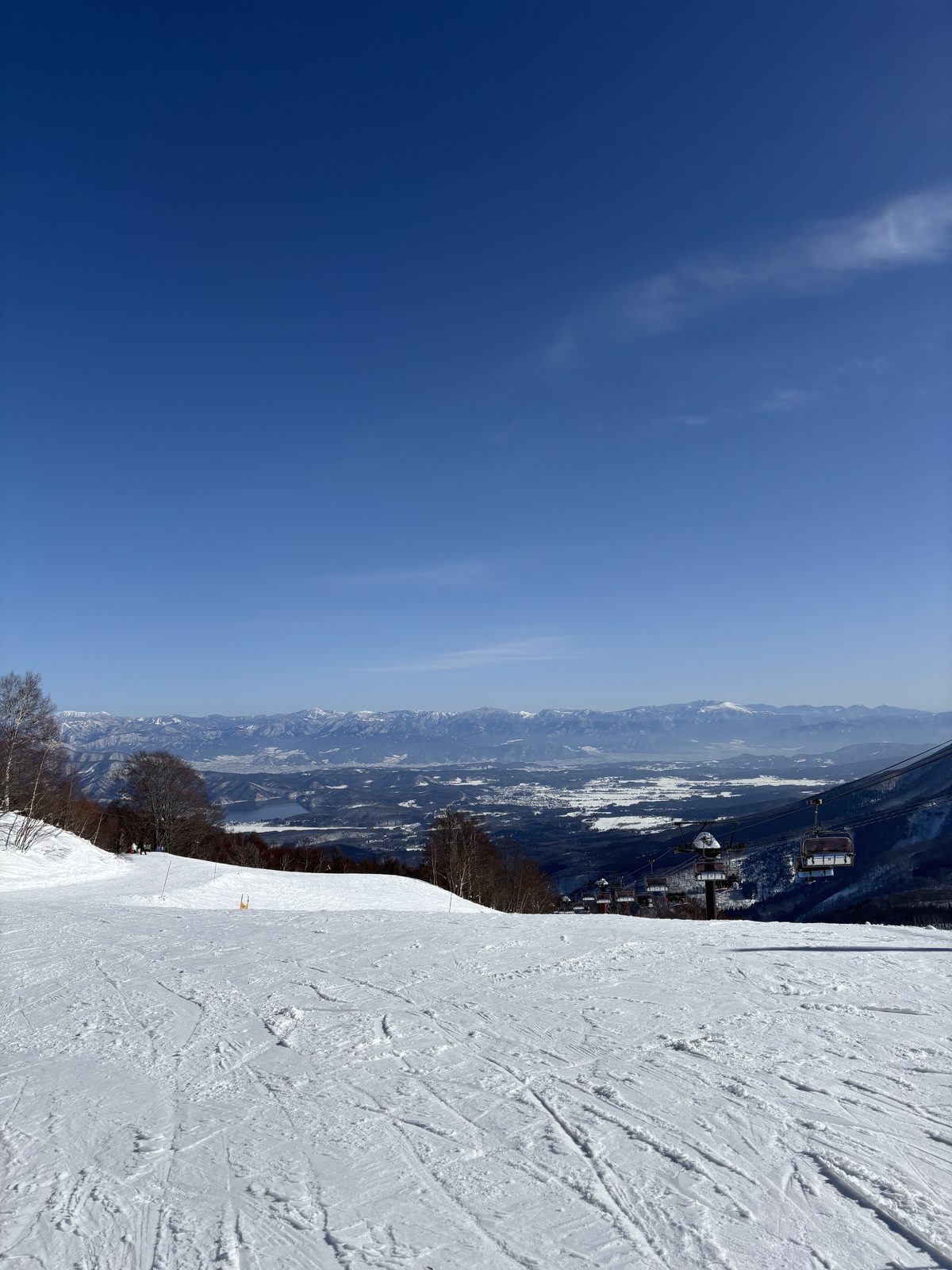 A high-speed lift, the basin and a lake below, and snowy ranges beyond