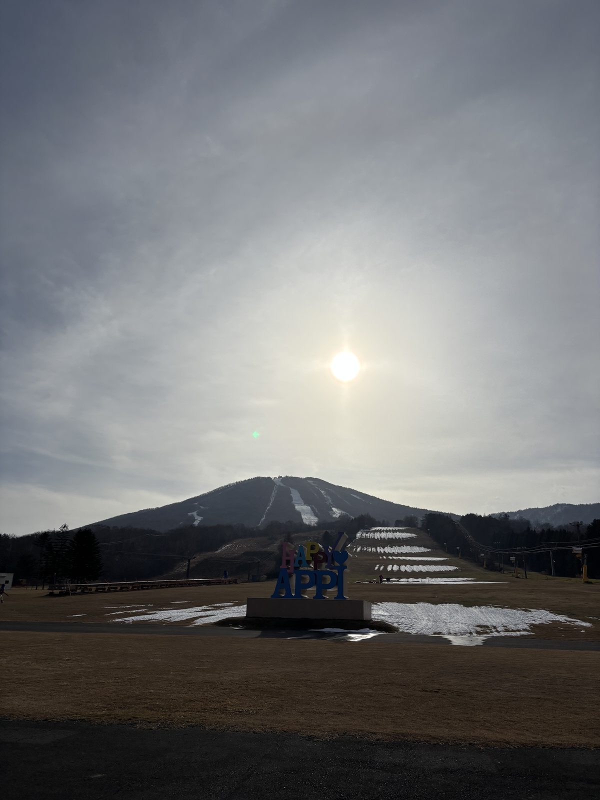 「HAPPY APPI」のオブジェ越しに見る、雪の少ない時期の安比の山