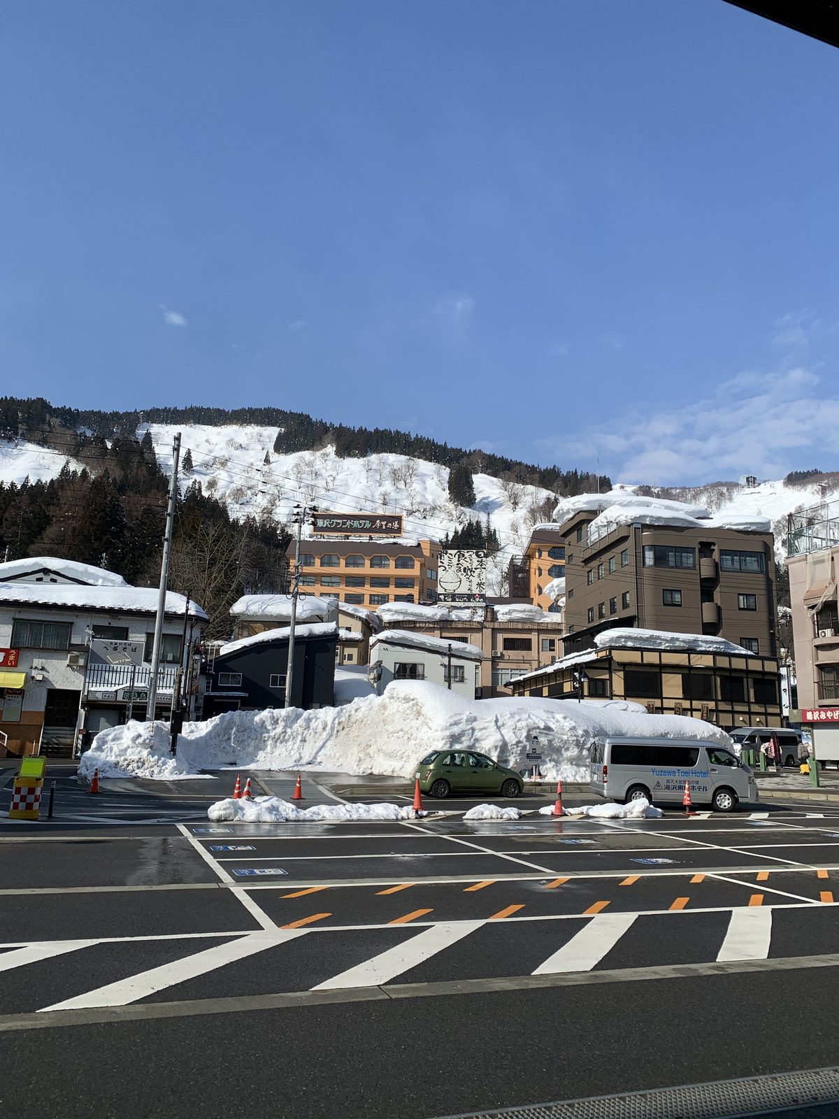 Rooftops and ploughed snow in Echigo-Yuzawa, with a ski slope rising behind the town