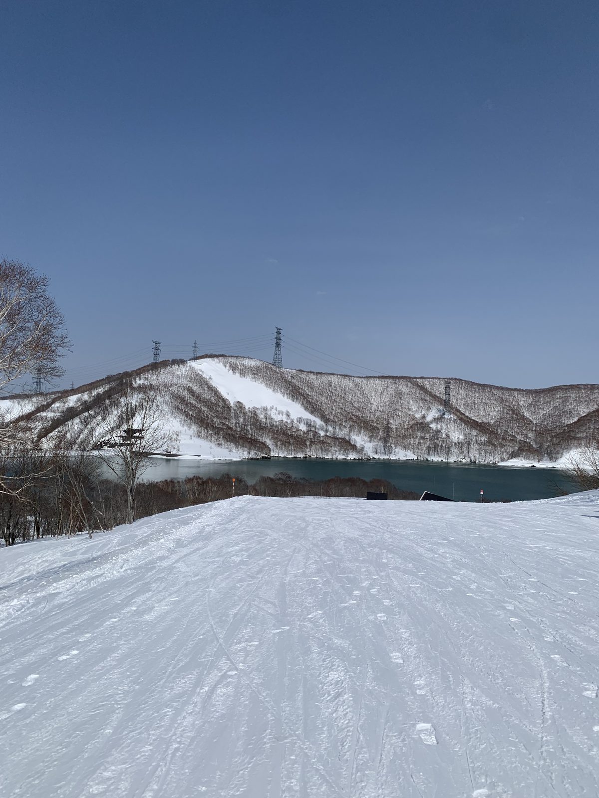 湖と雪の山に向かって下る整地された斜面